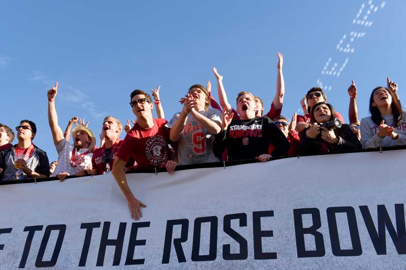 Fans cheering in front of a Rose Bowl sign