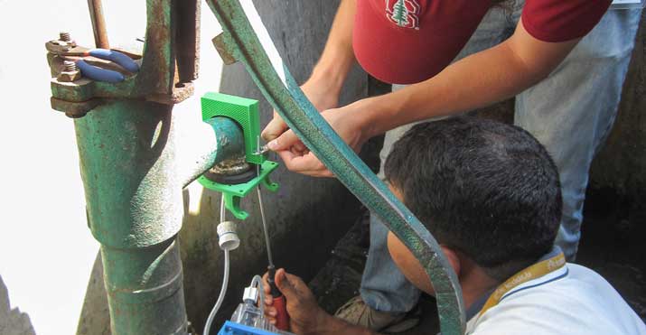 Frederick Goddard, graduate student in civil and environmental engineering, and a Bangladeshi field assistant install an automatic chlorination prototype at a handpump in Dhaka.