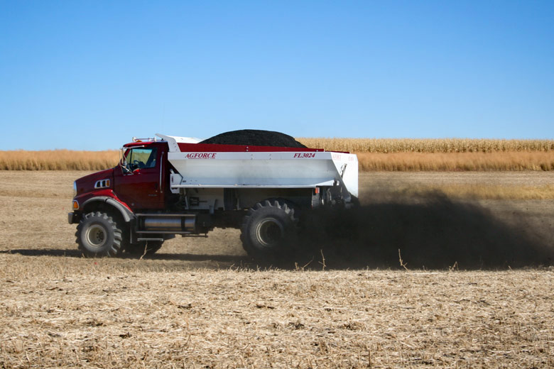 Truck spreading biochar on field