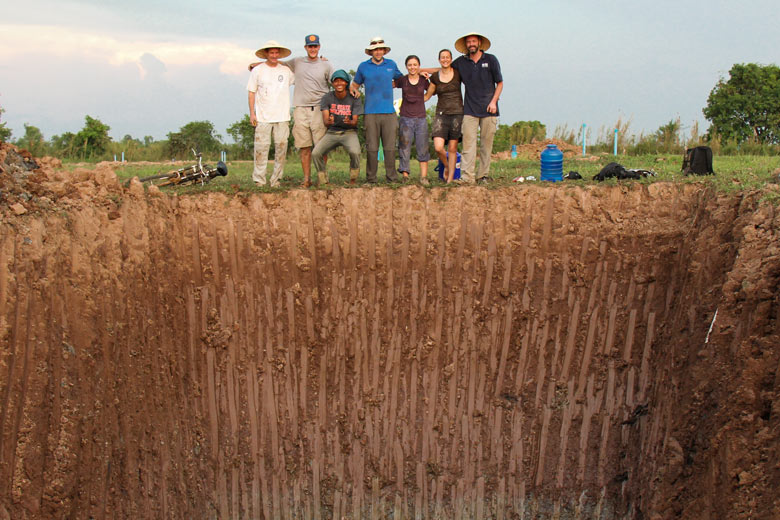 research team standing at edge of pit