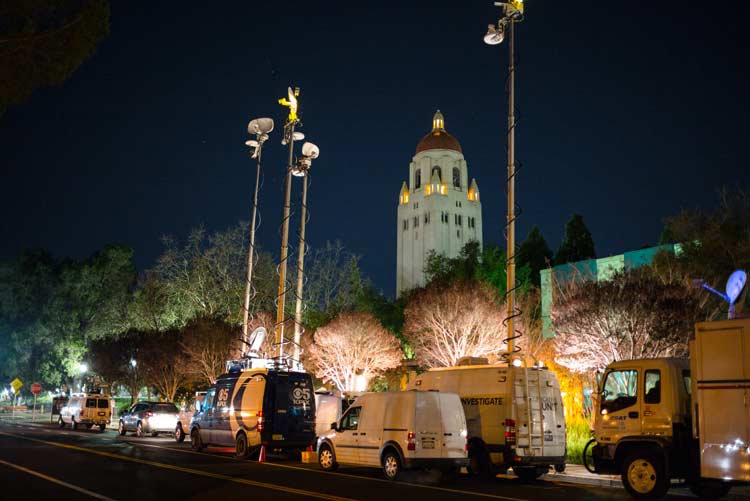 Media trucks lined up along Galvez Street with Hoover tower in the background. 