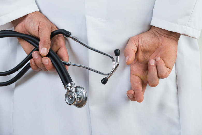 white-coated doctor with hands behind his back; one hand has fingers crossed in gesture indicating he's lying