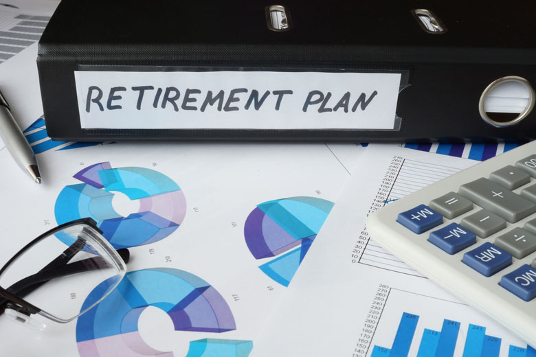 binder labeled 'retirement plan' with charts and calculator on desk