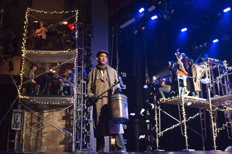 band members visible in scaffolding towers on stage