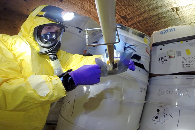 worker taking samples from a damaged drum at the Waste Isolation Pilot Plant 