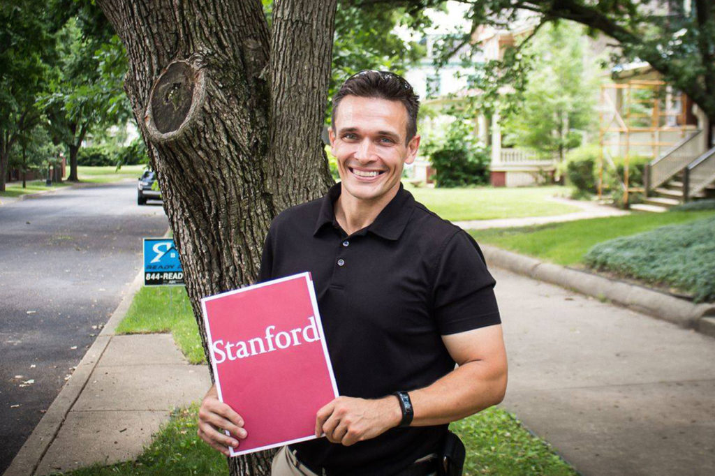 Jason Spyres holding a folder with Stanford logo on the cover