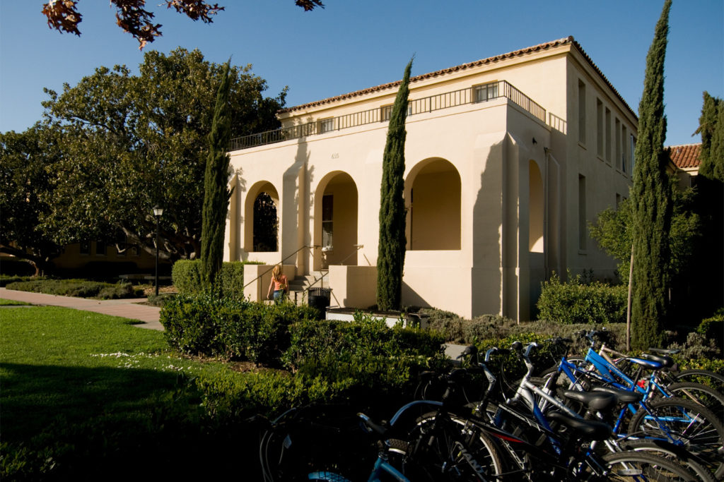 Photo of a student walking in front of Branner Hall as viewed from the bike racks.