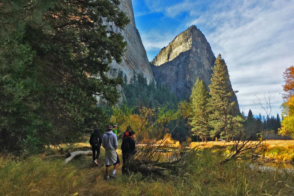 Students standing in field with trees and mountains in the background