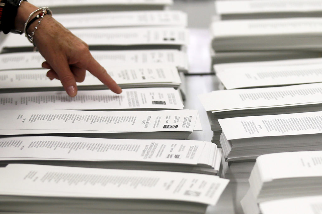 Hand pointing to a stack of ballots