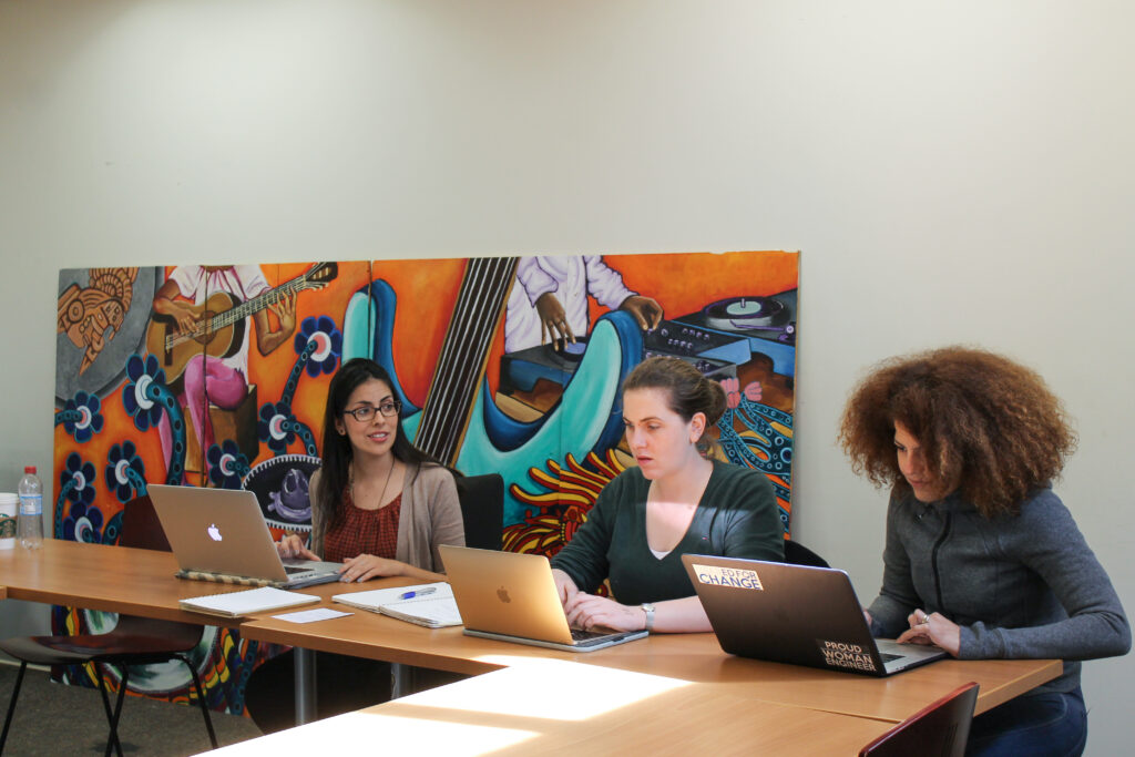 Three people working on laptops at the same table