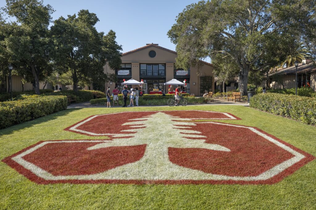 Shows a typical student residence with the Stanford logo painted on the front lawn.