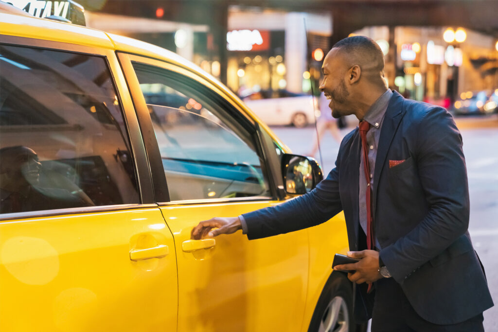 Smiling businessman getting in typical yellow taxi cab.