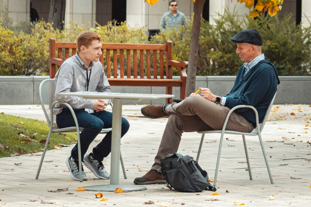 Two people sitting outside at engineering quad talking or networking