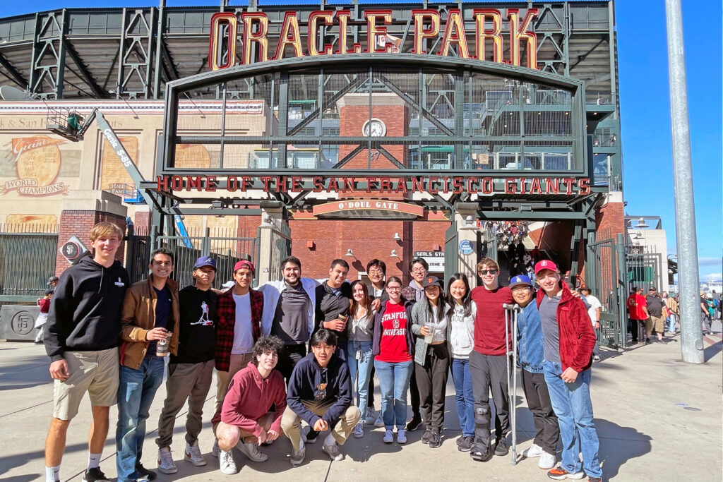 Group shot of several dozen students standing in front of the Oracle Park entrance sign, an example of the kinds of trips planned for the Explore the Bay series.