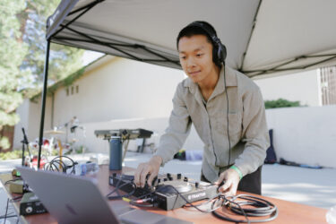 Student wearing headphones, operating a computer.