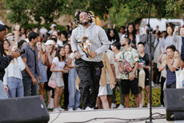 Performer jogging on stage, with a huge crowd of students in the background.