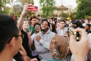 Performer in foreground, student crowd in the background.