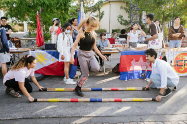 Student jumping over two poles on the ground, demonstrating tinikling