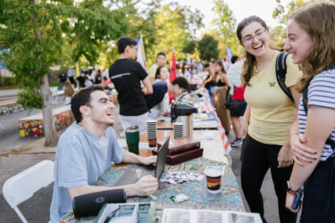 Students staffing a table, with many other student groups around them