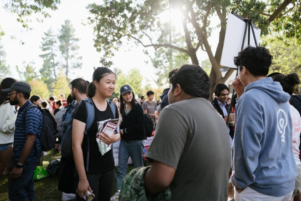 Two students talking in White Plaza in the foreground, with many students around them also talking with friends.