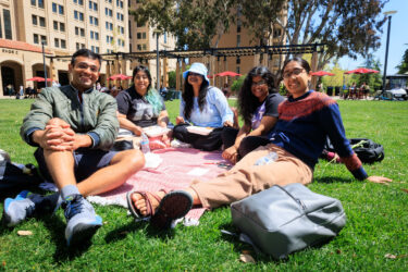 Five students seated on the lawn.