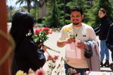 Staff member giving student a flower.