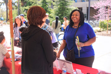 A staff member speaking to a student at a table.