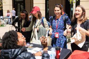 Staff members speaking to students at a table.