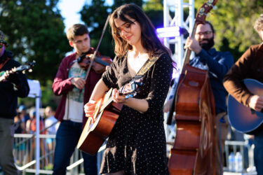 Student playing a guitar on stage.