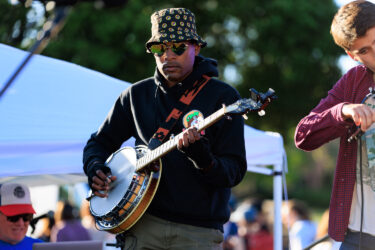 Student playing a banjo on stage.