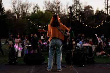 Student playing a guitar on stage.