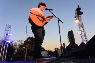 Student playing a guitar on stage.