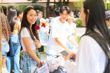 Two students speaking with a third student.