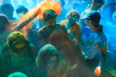 Students being covered in colored dust, smiling.