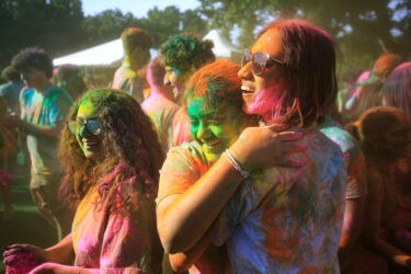 Students covered in colored dust, smiling.