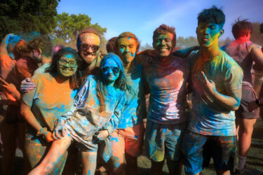 Students covered in colored dust, smiling.