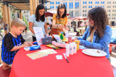 Students and their children at a table with craft supplies.