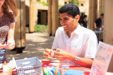 Student seated at a table making a card.