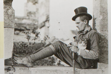 This photo of a cat curled safely in the lap of a man perched on a stone wall is from an album of World War I photographs depicting the activities of the American Expeditionary Forces in France. It is captioned: “This American soldier is not worrying over the dangers and perils of war.”