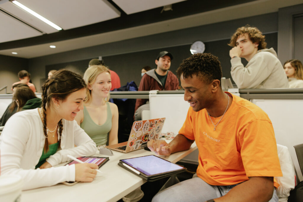 Three groups seated around a small group table inside a classroom.