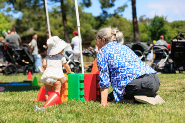 Toddler standing near a giant Lego block.