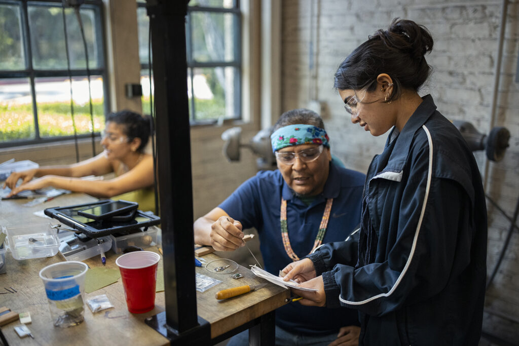 Artist Robert Blackhat Jr. works with a student.