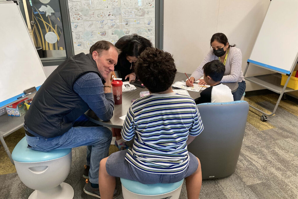 Professor Chris Lemons talks to a student in the small-group work area.