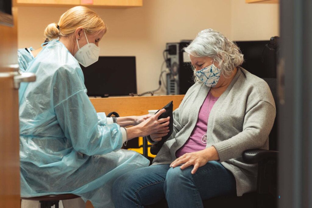 Postdoctoral researcher Caitlyn Seim takes measurements with a participant in the clinical trial of the vibrating glove to reduce muscle spasms in stroke patients.