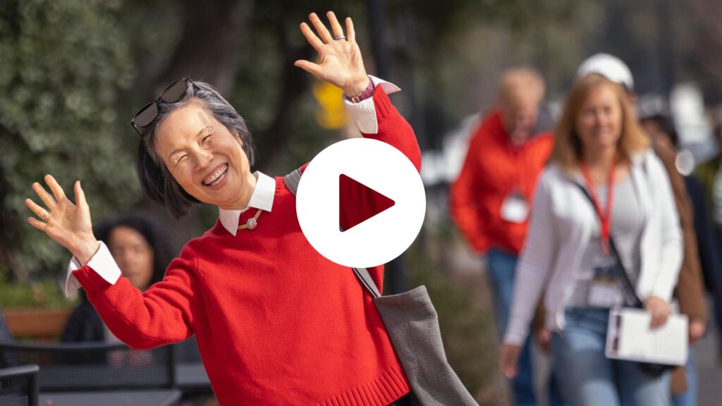 A visitor in a bright red sweater smiles for the camera after leaving a campus event during Family Weekend 2024