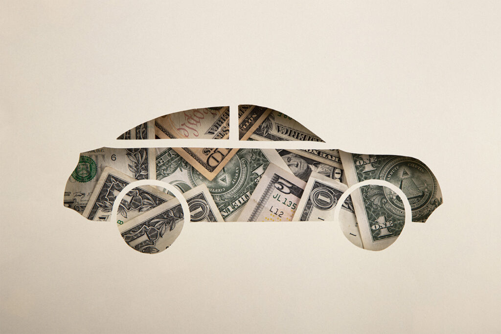 a car shape cut out of paper with money showing through from behind.