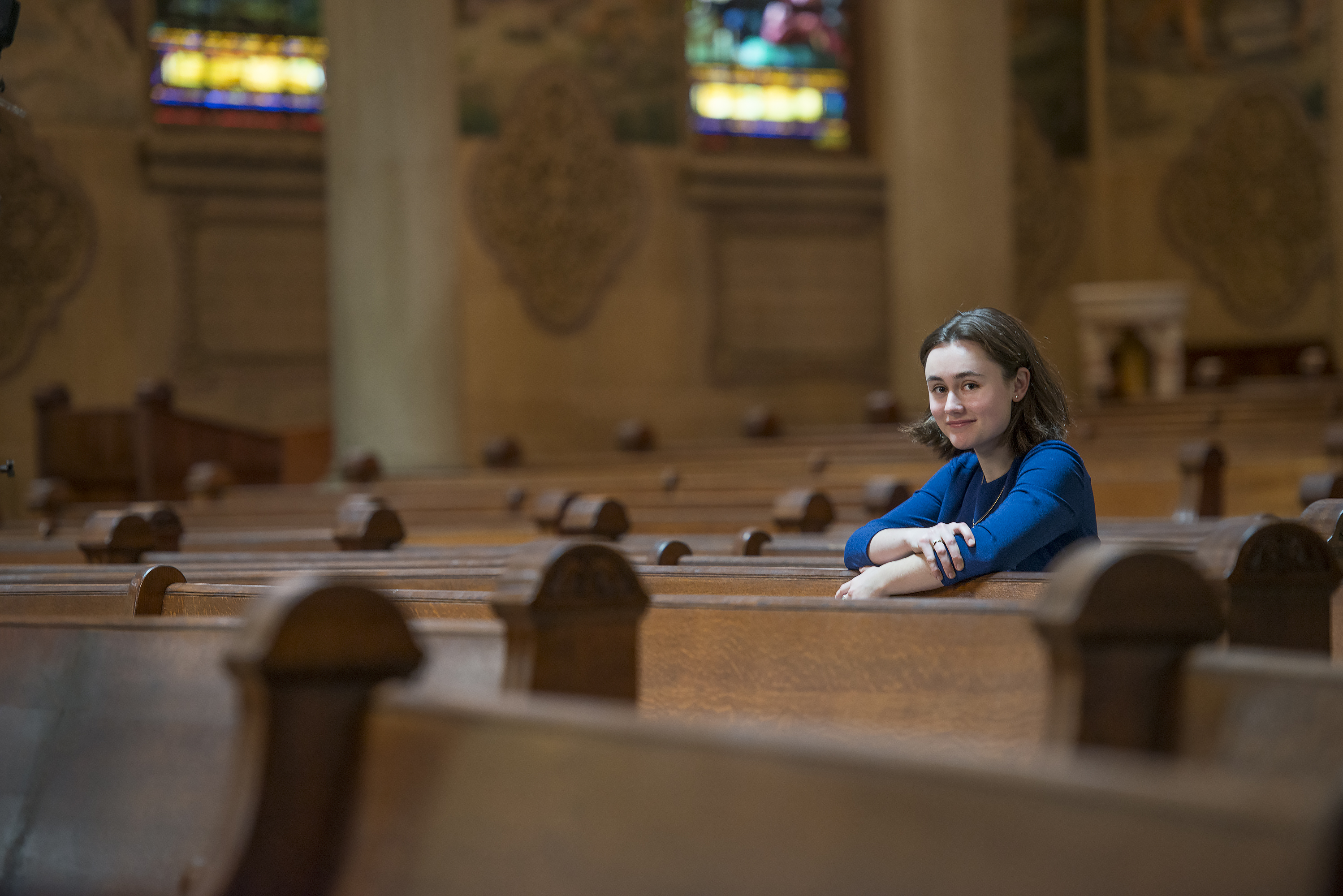 Student Christina E.C. Smith photographed among the pews in Memorial Church. (Smith studies medieval wood carvings called misericords.)