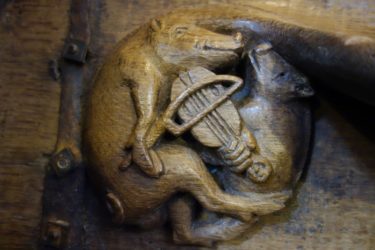 A boar plays the fiddle on this misericord in Winchester Cathedral.