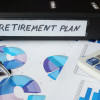 binder labeled 'retirement plan' with charts and calculator on desk / designer491/Shutterstock