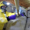 worker taking samples from a damaged drum at the Waste Isolation Pilot Plant